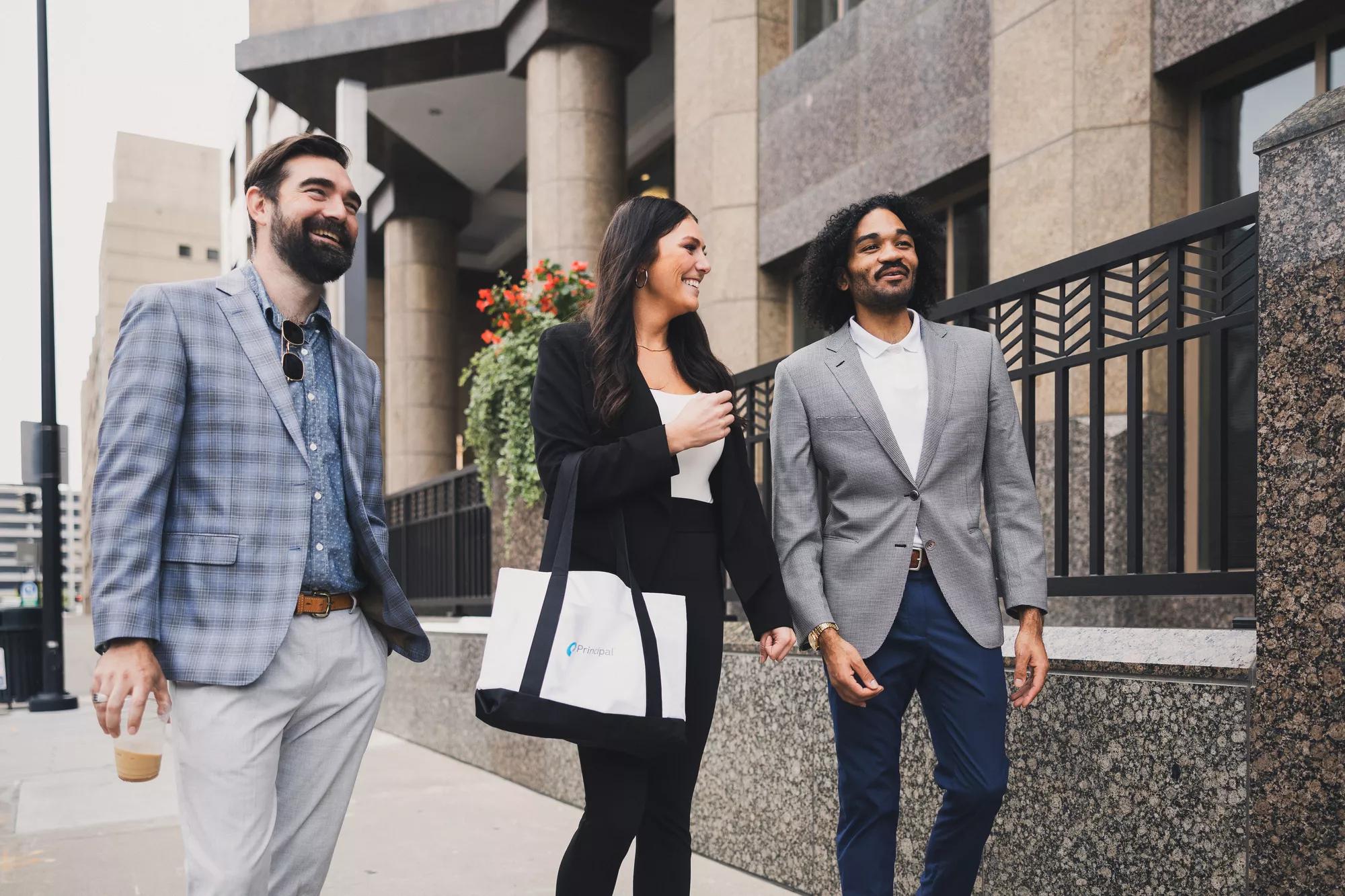 Three people walking outside of a Principal building. Three people walking outside of a Principal building.